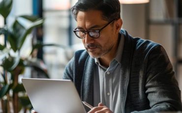 Small business owner reviewing a cybersecurity checklist on a laptop in a modern office